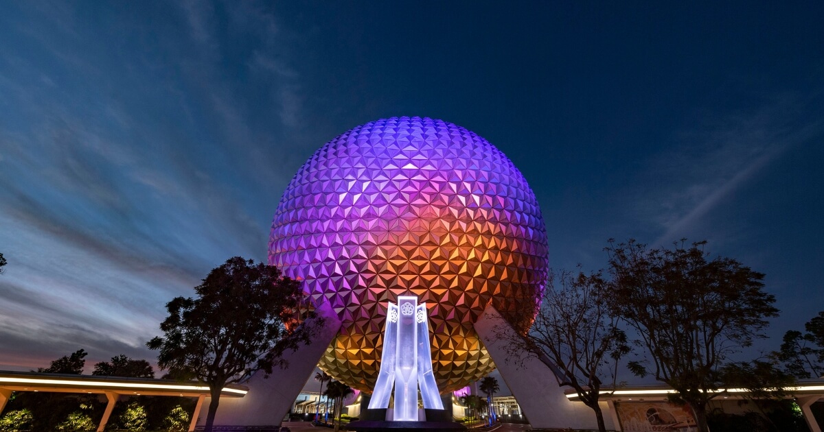 Photo of Spaceship Earth at Epcot at night with blue, purple, fuchsia, and rusty lights on it.