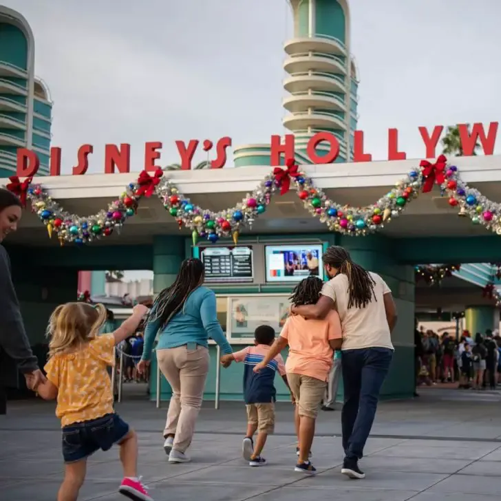 Photo of people walking up to the Hollywood Studios main entrance, which is decorated for Christmas.