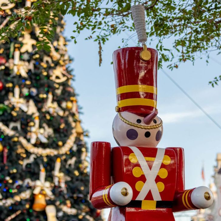 Photo of a toy soldier statue with Magic Kingdom's Cinderella Castle and a Christmas tree in the background.