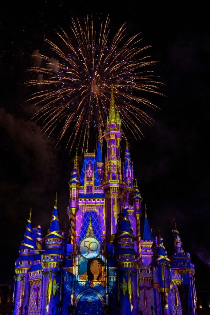 Photo of Cinderella's castle at Disney World's Magic Kingdom at night with a firework bursting above it.