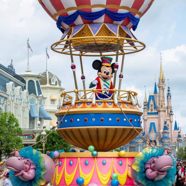 Photo of Mickey Mouse on a parade float waving at guests at Magic Kingdom.
