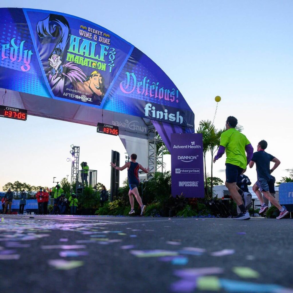Photo of the finish line with racers running by at the Disney Wine & Dine Half Marathon.