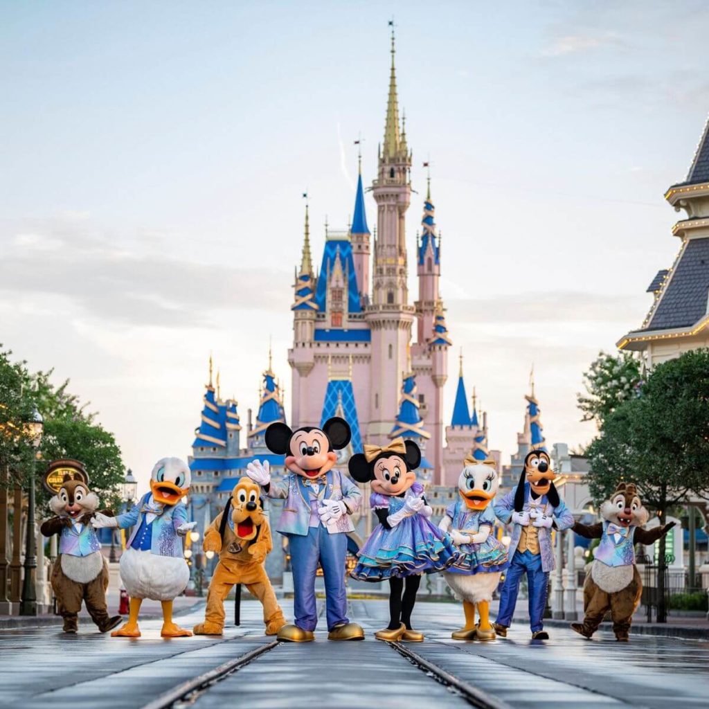 Photo of Disney characters in EARidescent costumes posing in front of Cinderella Castle at Magic Kingdom.