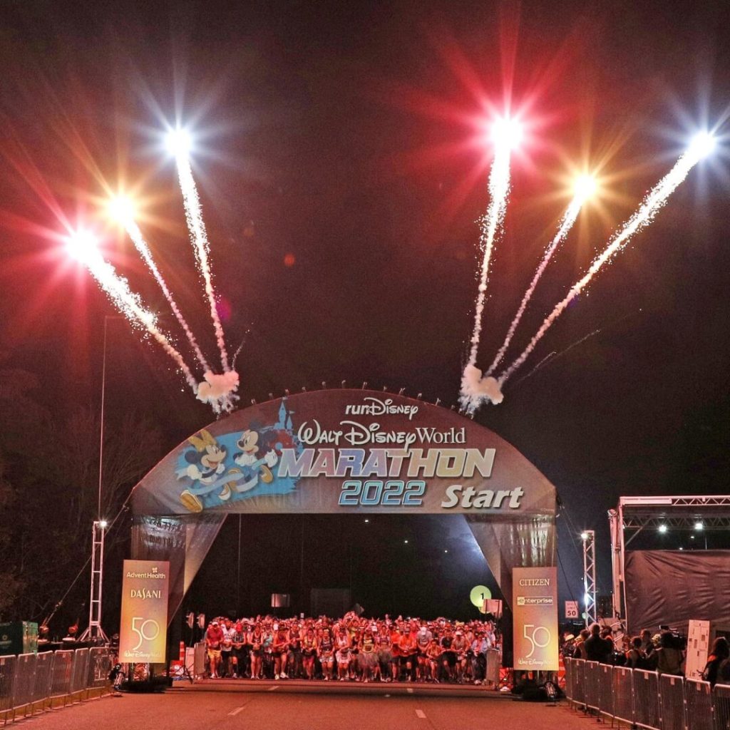Photo of the start line at the Walt Disney World Marathon 2022 start line with fireworks bursting from the top of the sign.