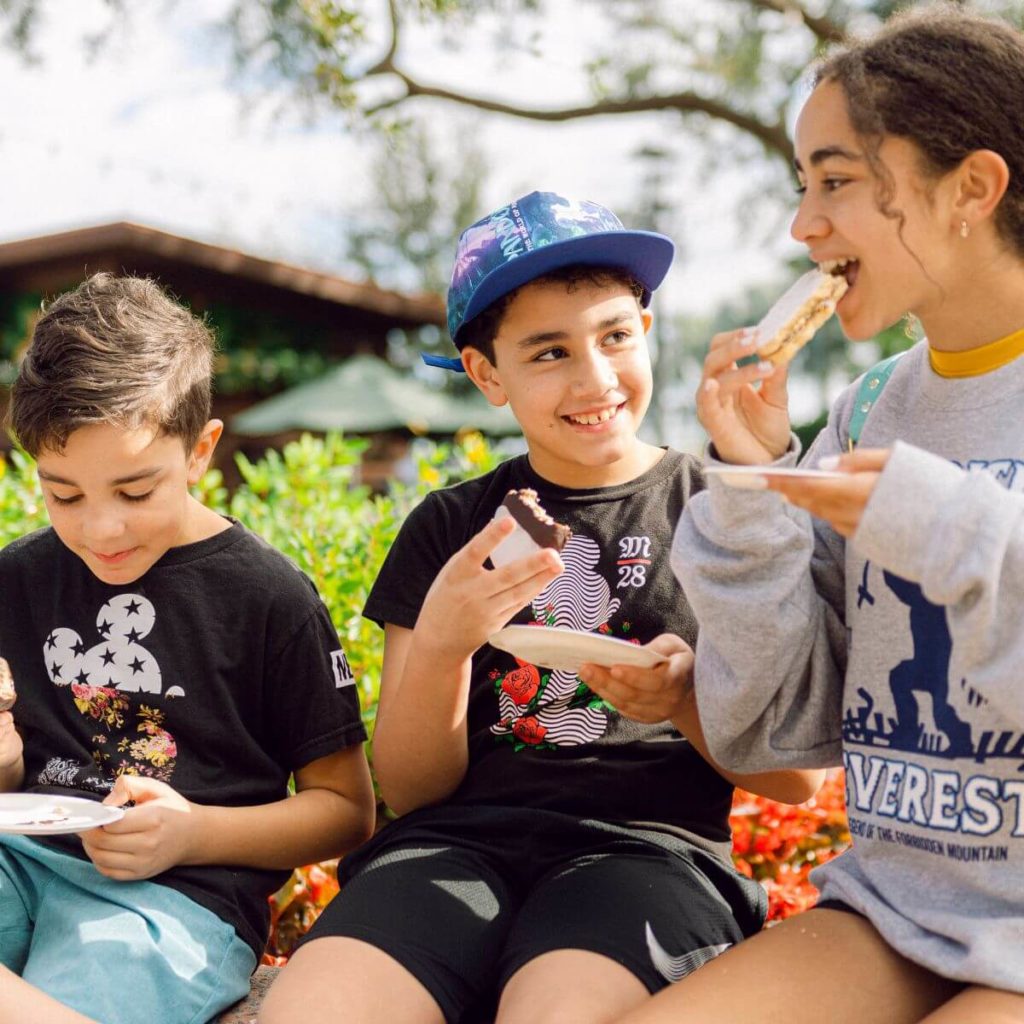 Photo of a group of 3 kids enjoying snacks at Disney World.