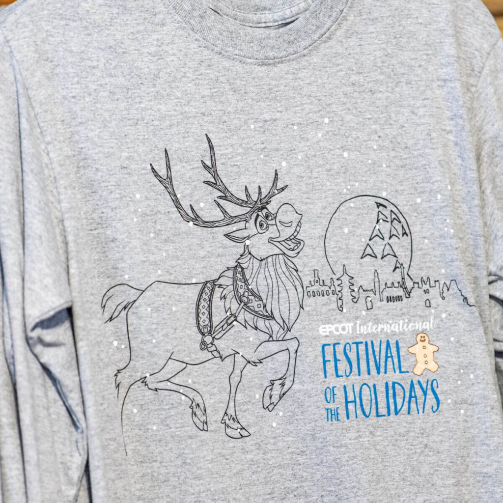 Closeup photo of a long-sleeved t-shirt with Sven from Frozen, the Epcot ball, and World Showcase. Text on the shirt says "Epcot International Festival of the Holidays."