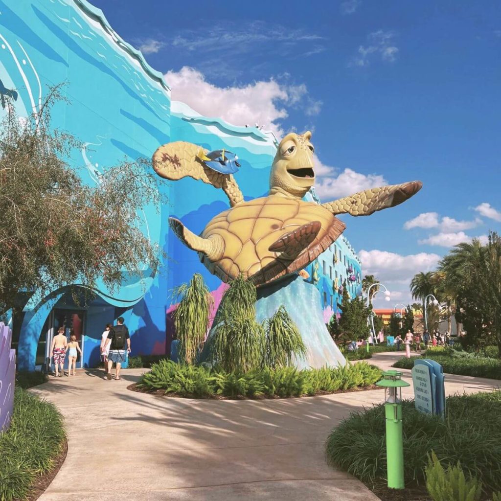 Photo of a giant Crush and Dory statue at the Art of Animation Resort at Disney World with families walking nearby.