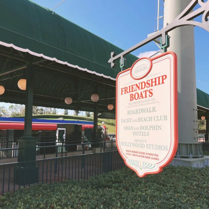 Photo of sign that says "Friendship Boats" and lists multiple stops throughout Walt Disney World Resort, with a boat parked in the background.