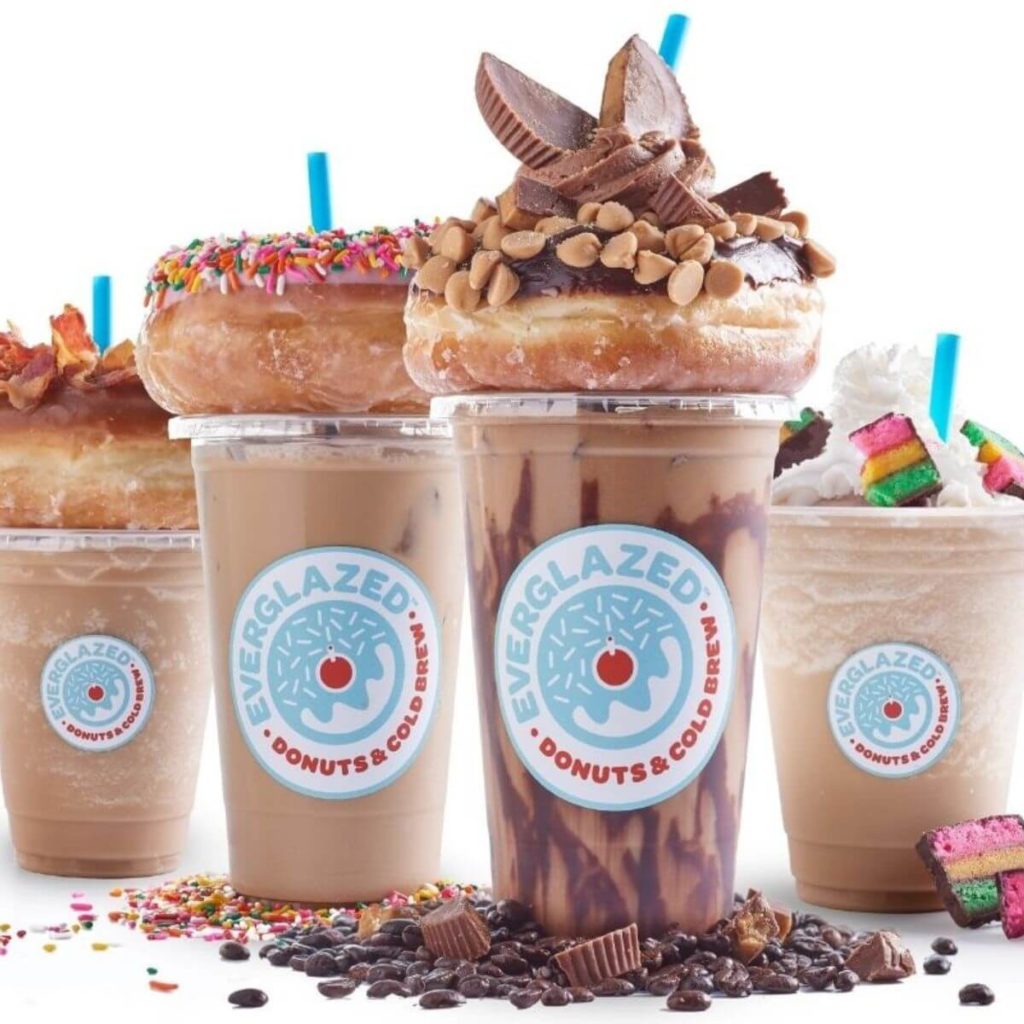 Photo of cold brew coffees and iced lattes with elaborate donuts on top.