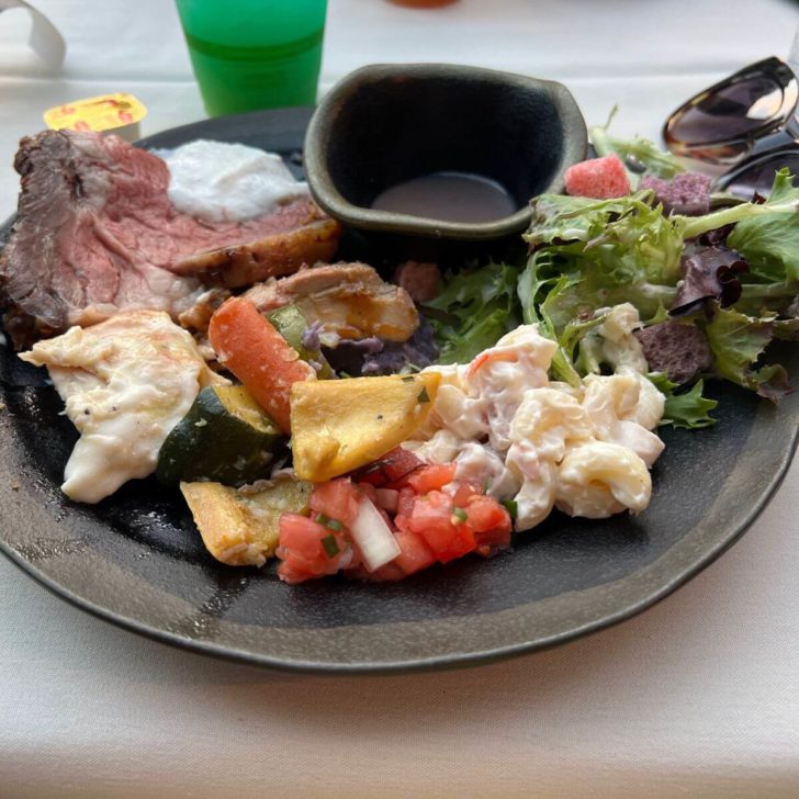 Photo of a plate filled with food from the Aulani Luau buffet, including lomi lomi salmon, poi, mac salad, and more.