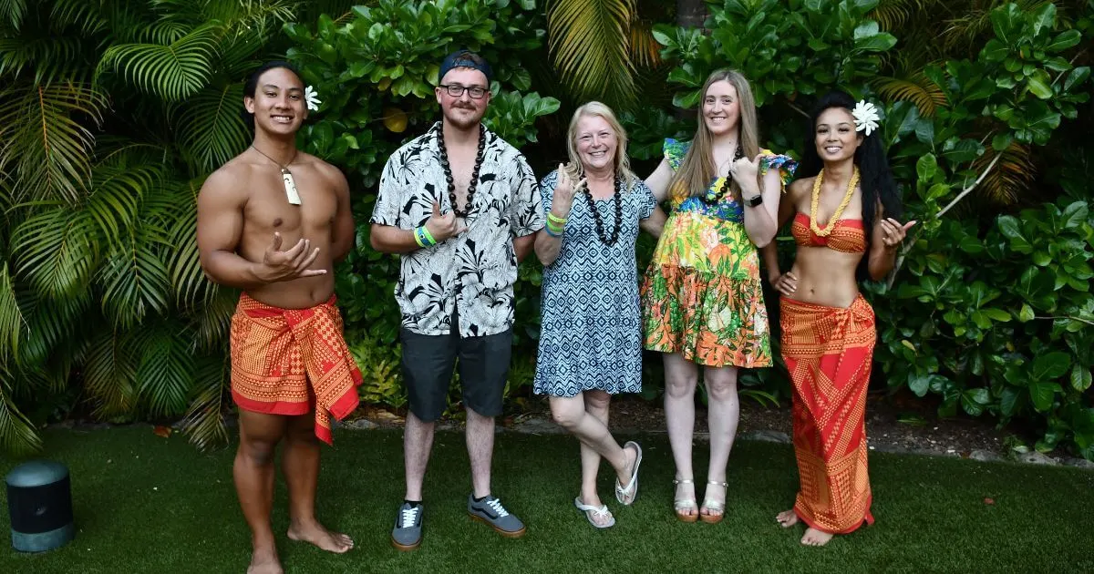 Horizontal photo of a family posing with performers from the Disney Aulani Luau.