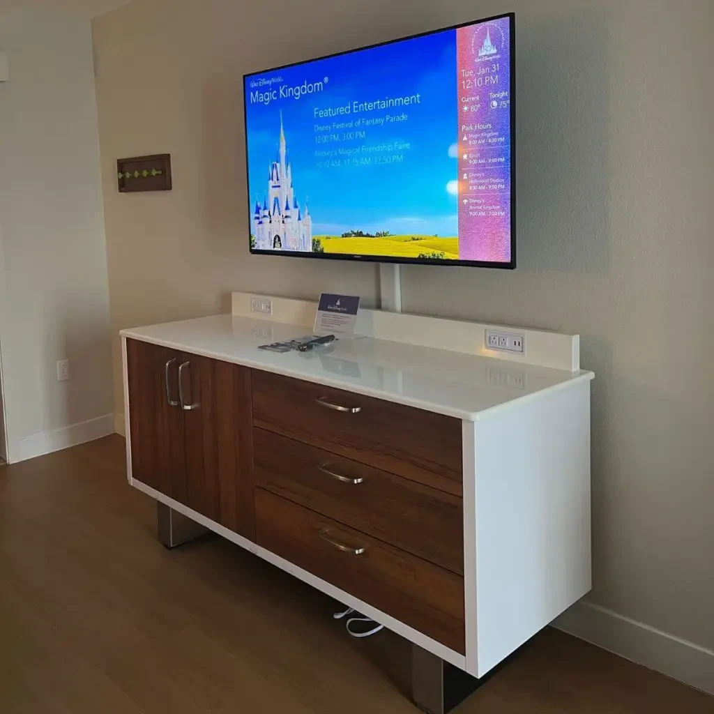Photo of a flat screen tv above a dresser with Disney World resort TV turned on.