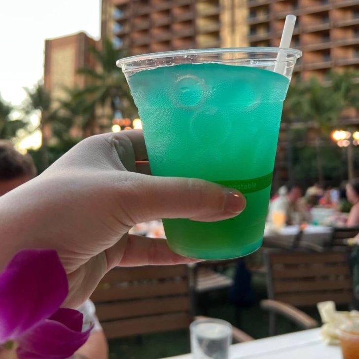 Closeup of a woman holding a Blue Hawaiian cocktail.