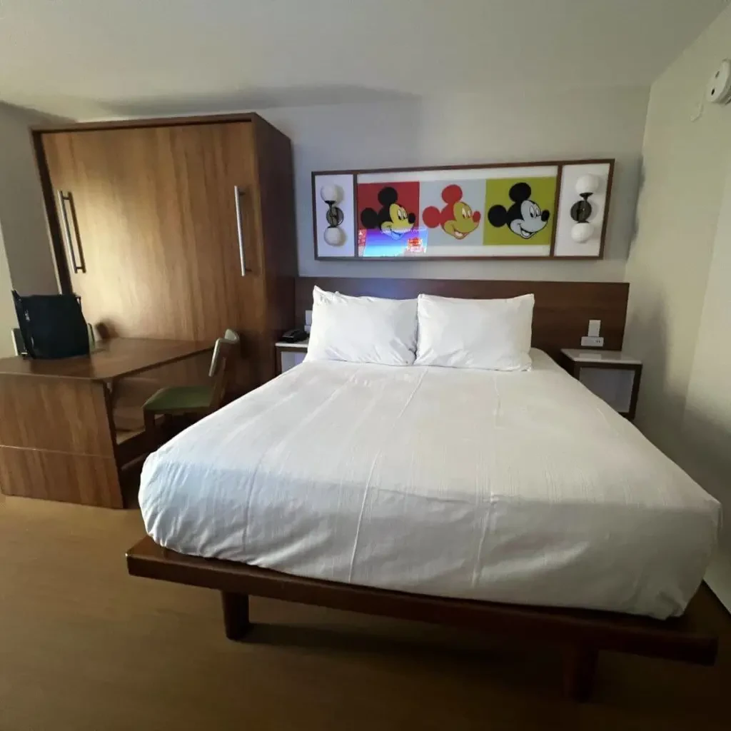 Photo of the interior of a Pop Century preferred room with 1 queen bed and 1 queen murphy bed that is closed to show a table instead.