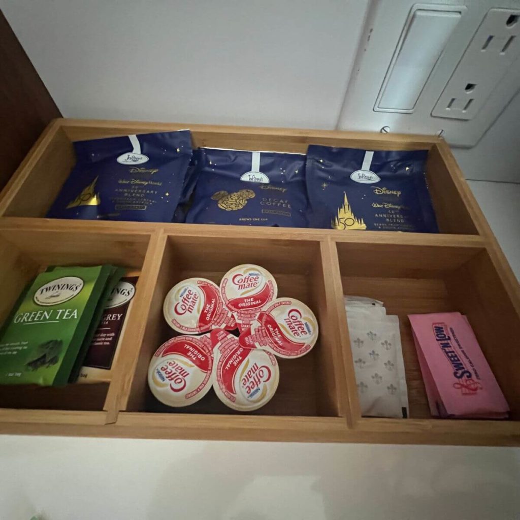 Closeup photo of a tea and coffee caddy with coffee pod packets, tea sachets, creamer pods, and sugar & sweet-n-low packets.