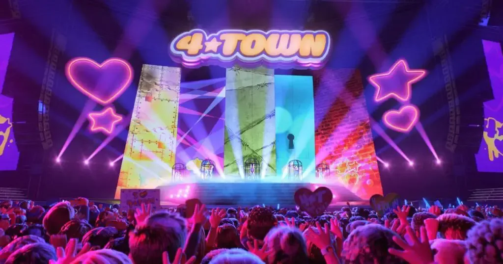 Photo still from a 4-Town concert with crowds in the foreground and a colorful stage in the background.