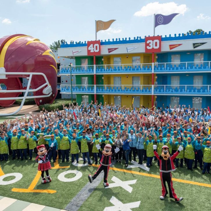 Photo of the staff posing in the courtyard of the All-Star Sports Resort with Minnie, Mickey, and Goofy in sports gear in the foreground.