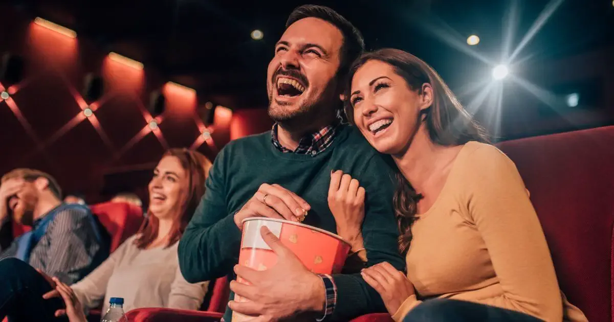 Photo of 4 adults sitting in the audience of a stage show, laughing.