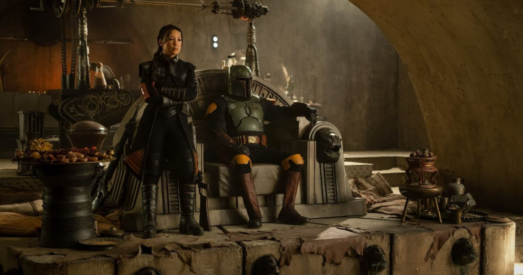 Photo still of Boba Fett on Jabba the Hutt's throne and Fennec Shand at his side.