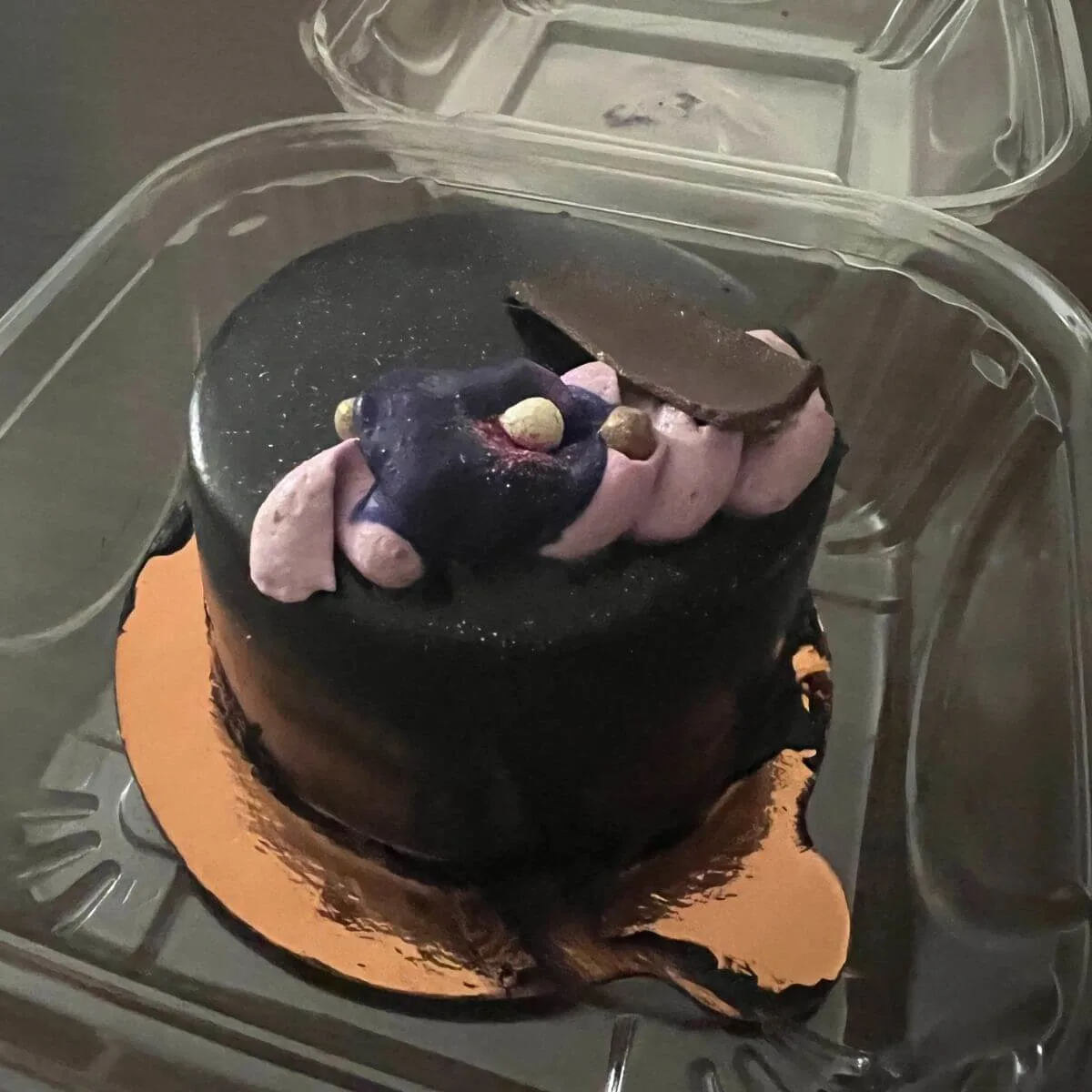 Closeup photo of a chocolate-ginger petite cake with purple iridescent garnish on top.