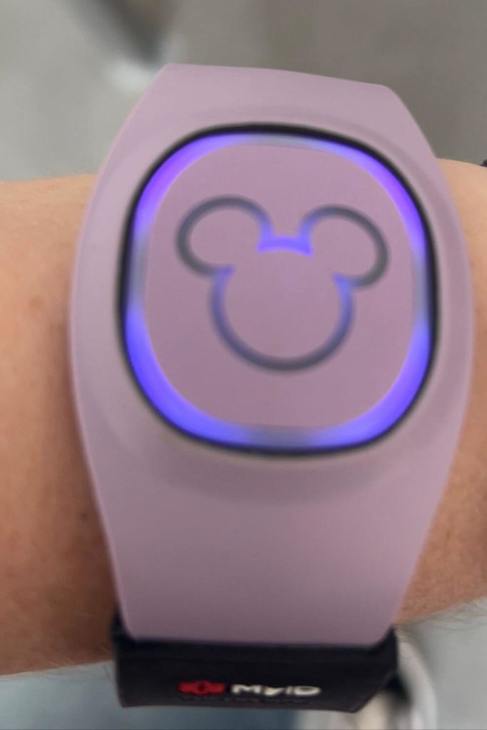 Closeup of a lilac MagicBand+ with purple glowing lights.