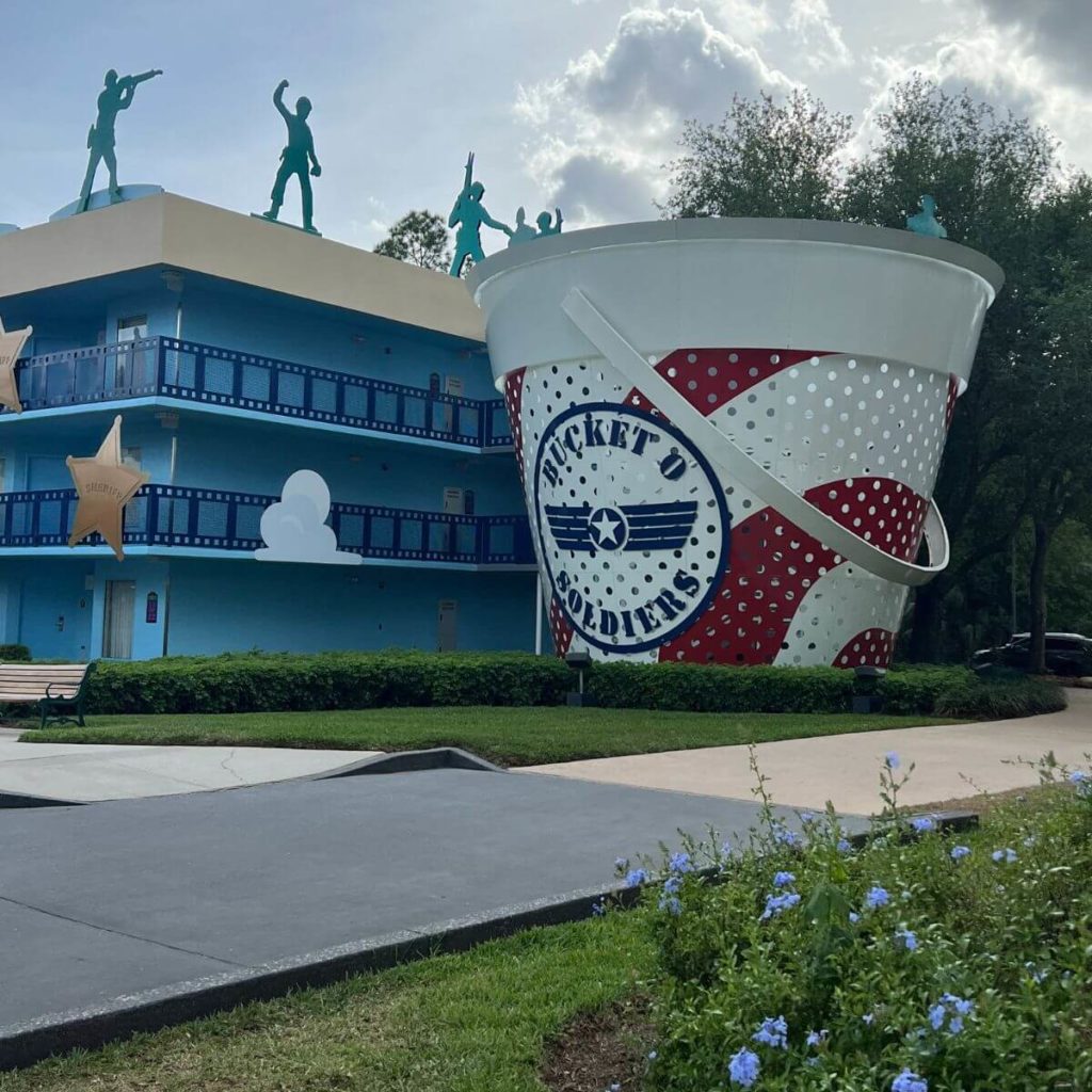 Photo of one of the resort guest room buildings in the Toy Story section at Disney's All-Star Movies resort with green Army men on the top and a giant "Bucket o' Soldiers" statue.