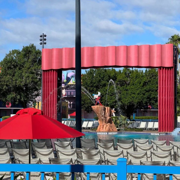 Photo of the main pool at the All-Star Movies Resort with lounge chairs in the foreground.