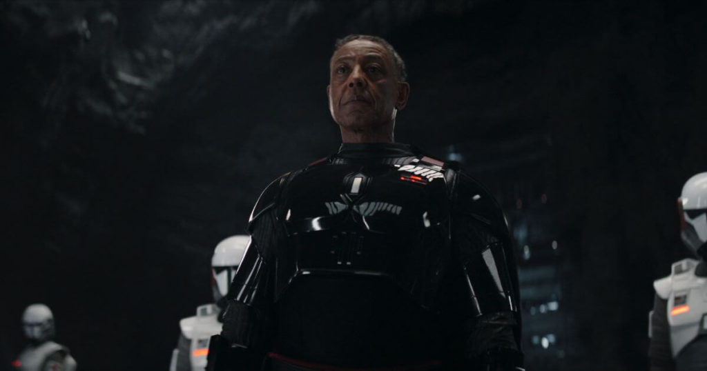 Photo still of a scene from season 3 of The Mandalorian with Moff Gideon (Giancarlo Esposito) in the center with Imperial armored commandos on each side.