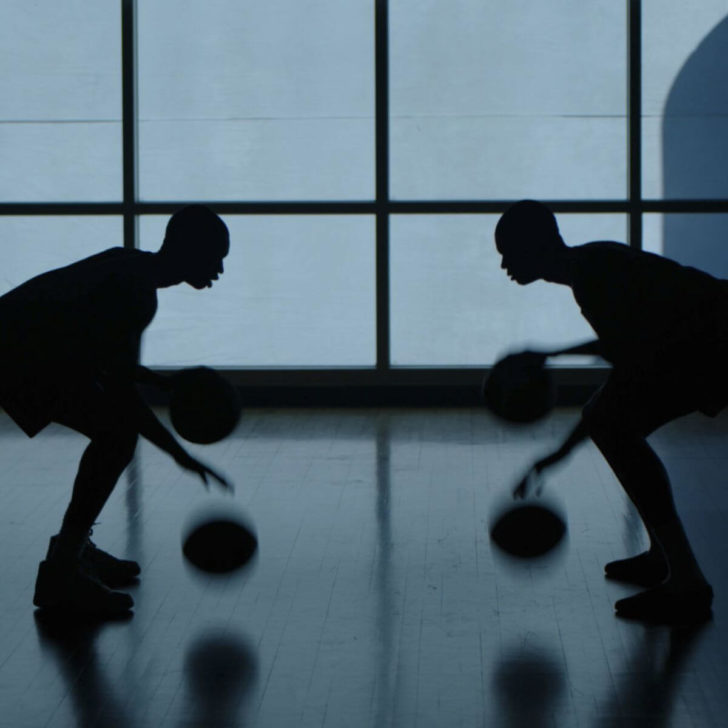 Still from the movie Rise, showing the silhouette of 2 young men dribbling basketballs.