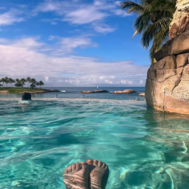 Photo from the Ka Maka Grotto pool overlooking the Aulani Lagoon, with 2 feet in the foreground.