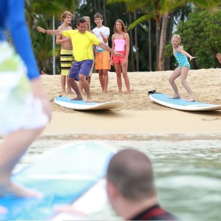 Photo of a man teaching kids how to balance on a surfboard.