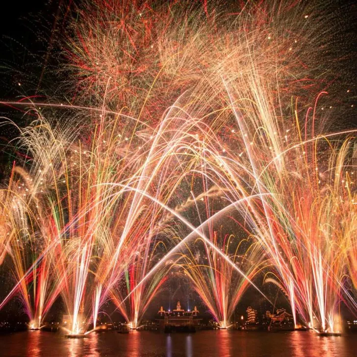 Photo of white, red, and green fireworks bursting straight up during the Epcot Forever nighttime show.