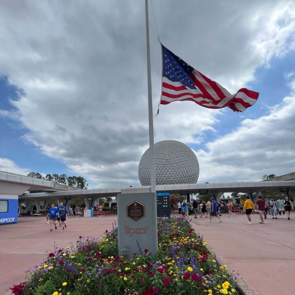 Photo of the main entrance at Epcot with an American Flag at half staff.