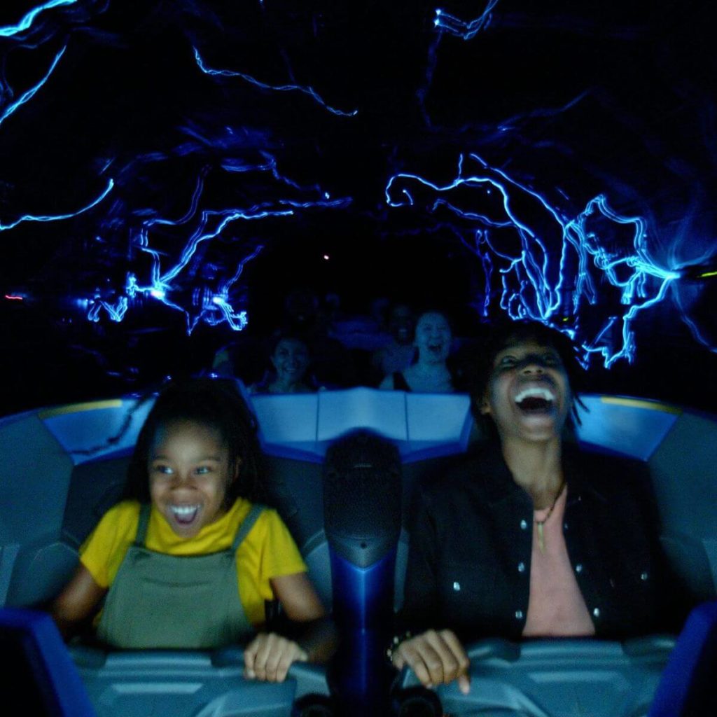 Photo of people riding the Cosmic Rewind roller coaster ride at Epcot with big smiles on their face.