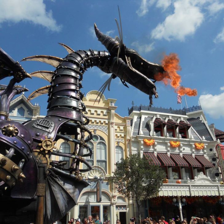 Photo of a large float of a purple metal dragon breathing that is breathing fire.