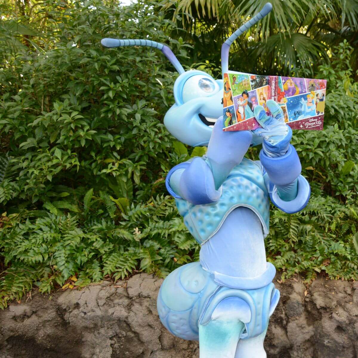 Photo of Flix from A Bug's Life signing a character autograph book.