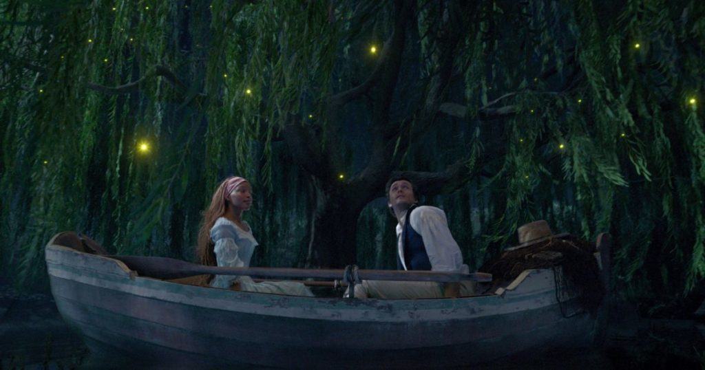 Photo still from the 2023 live-action film, The Little Mermaid, with Ariel and Prince Eric in a row boat.