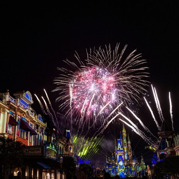 Photo looking down Main Street at Magic Kingdom with fireworks bursting over Cinderella's Castle.