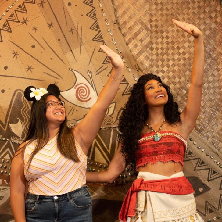 Photo of Moana posing with a young woman with their hands in the air as if using the stars for wayfinding.