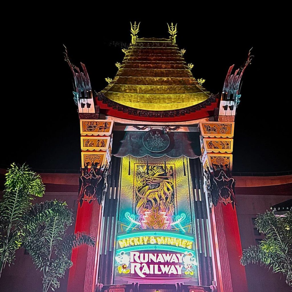 Photo of the entrance to Mickey & Minnie's Runaway Railway lit up in neon lights at night.