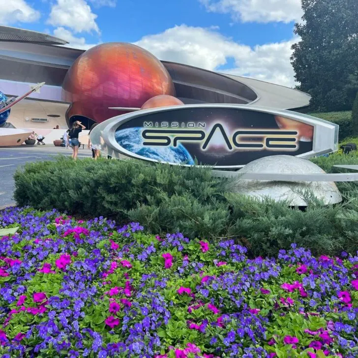 Photo of the exterior of the building for Mission: Space ride, with flowers in the foreground.