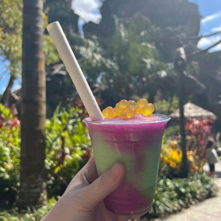 Closeup photo of a night blossom pink and green slushy with passion fruit boba on top.