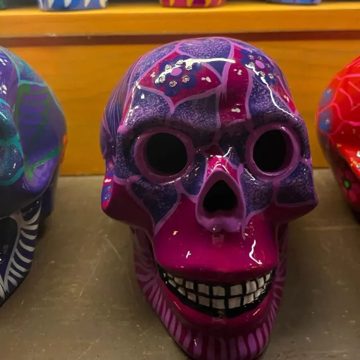 Closeup photo of a violet and purple painted skull for sale at a kiosk inside the Mexico pavilion at Epcot.