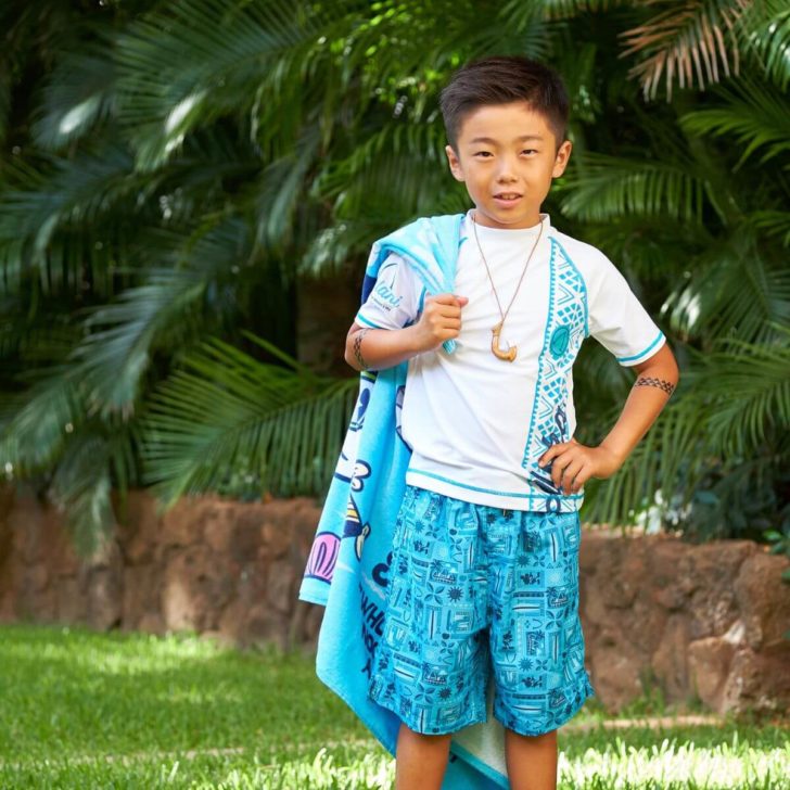 Photo of a young boy with a Hawaiian-style surfer makeover.