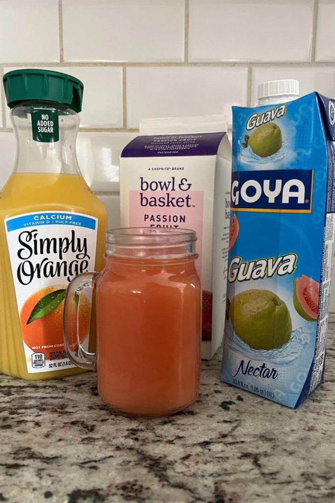 Photo of 3 bottles of juice: passion fruit, orange, guava, with a glass mug of POG juice in front.