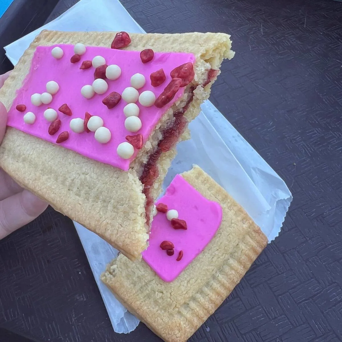 Closeup of a raspberry lunch tart broken in half to expose the jelly center.