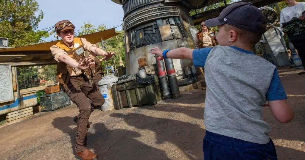 Photo of a Rise of the Resistance cast member playing with a young guest outside the ride entrance.
