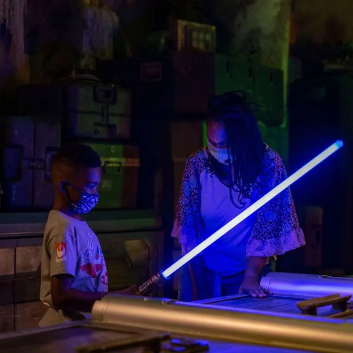 Photo of a young boy building a blue light saber with an adult woman.
