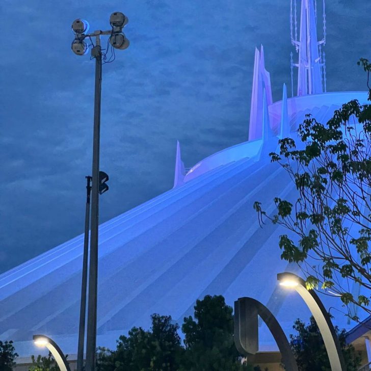 Photo of the Space Mountain building at night, light up in blue from the TRON roller coaster.