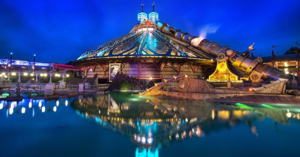 Photo of the exterior of Star Wars: Hyperspace Mountain at Disneyland Paris at night with the peak of the building reflecting in water in the foreground.